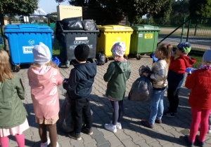 przedszkolaki wrzucają śmieci do odpowiednich koszy w przedszkolu